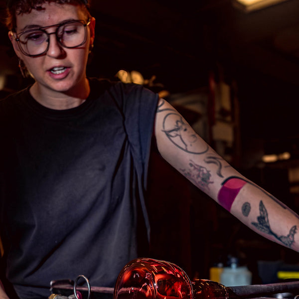 Person working with molten glass in a workshop setting